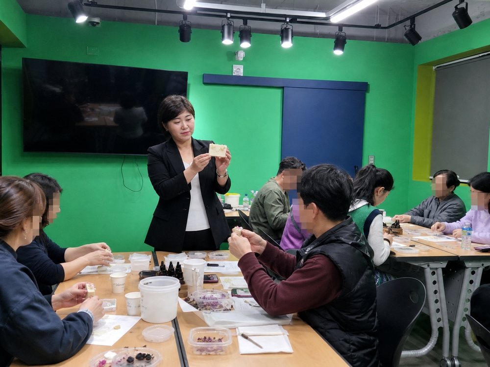 완성된 천연비누를 들어 보이며 설명하는 강사와 참여자들