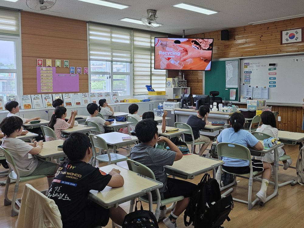 초등학교 교실에서 재활용 주제 영상을 보고 있는 학생들